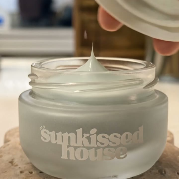 A Sunkissed House skincare jar opened, dispensed and used in warm natural light